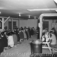 People seated in a mess hall at a farewell party for Julius Egashira