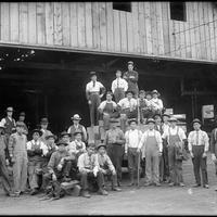 Workers largely of Asian descent in front of a warehouse